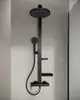 Duschsystem von Ideal Standard mit großem Kopfbrause und Handbrause. Es verfügt über zwei Ablagen und ein schlankes, schwarzes Design. Montiert in einem modernen Duschebereich.
